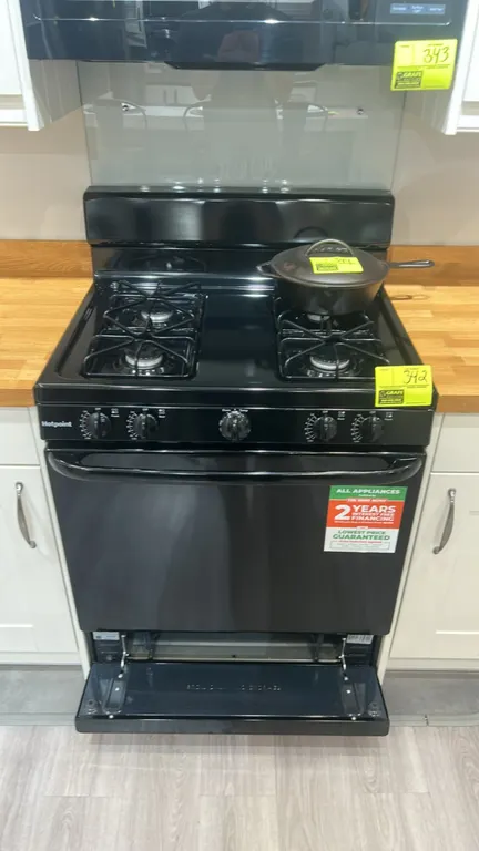 Hotpoint RGBS300DM2BB 4-burner gas range. Features black finish, front dial controls, two interior oven racks, and lower broiler drawer. 30"W. S/N: ZS