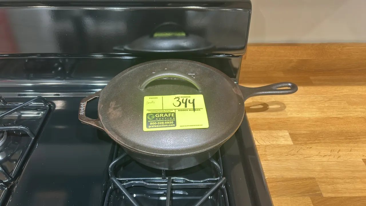Assorted kitchen smallwares. Includes a Lodge cast iron deep skillet with matching cast iron lid, and (4) ceramic dinner plates. Range and cabinetry n