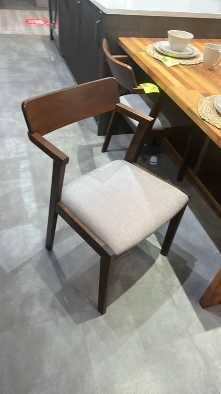 Dining armchair. Features a solid wood frame with a walnut-tone finish, curved backrest, integrated armrests, and an upholstered fabric cushioned seat