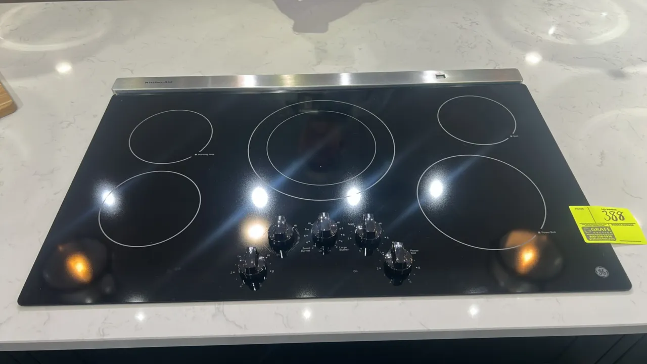 GE Appliances JP3036DL3BB 36" 5-burner electric cooktop with KitchenAid pop-up range vent. Features smooth black glass-ceramic surface, dual-ring cent