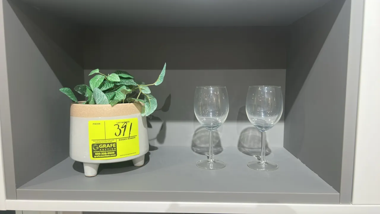 Assorted decorative smallwares. Includes (1) ceramic footed planter with artificial plant and (2) stemmed wine glasses. Display shelving not included.