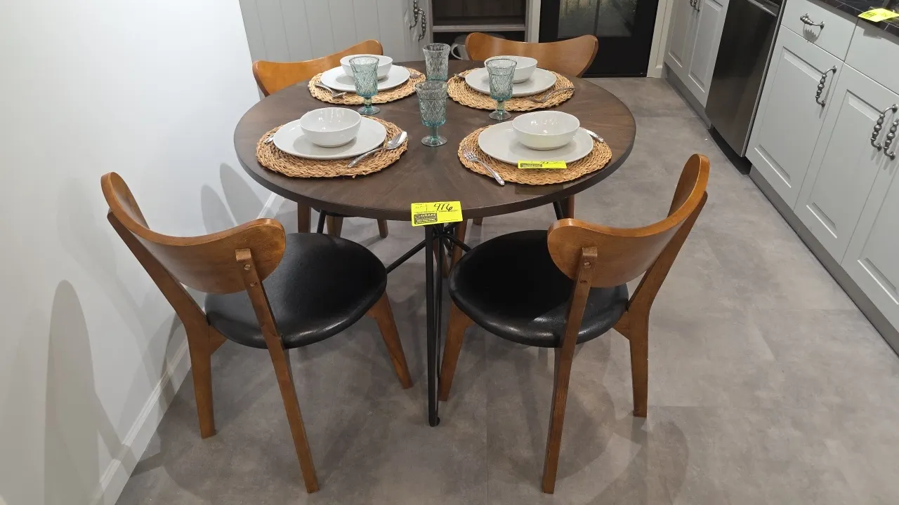 Dining table set. Includes round wood dining table and (4) wood dining chairs with black faux leather upholstered seats. Table features a dark wood fi