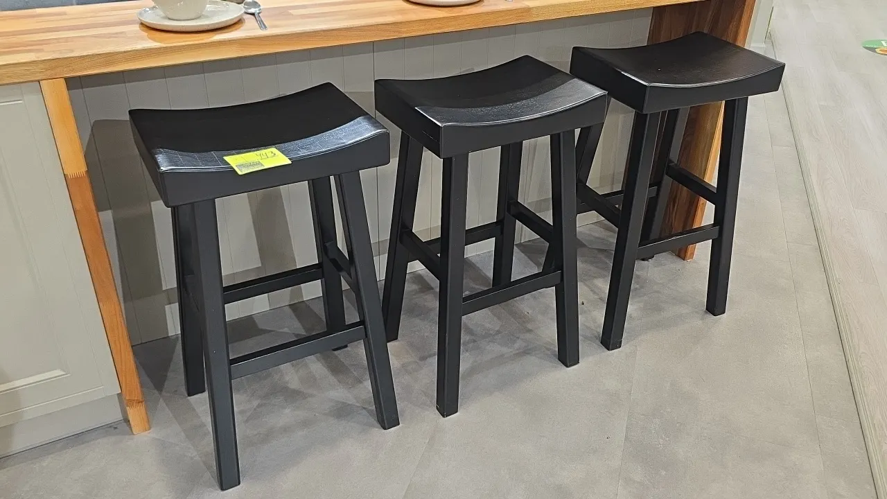Solid wood barstools. Features contoured saddle seats, four-leg base, and integrated footrest stretchers. Finished in black. Bar counter and tabletop