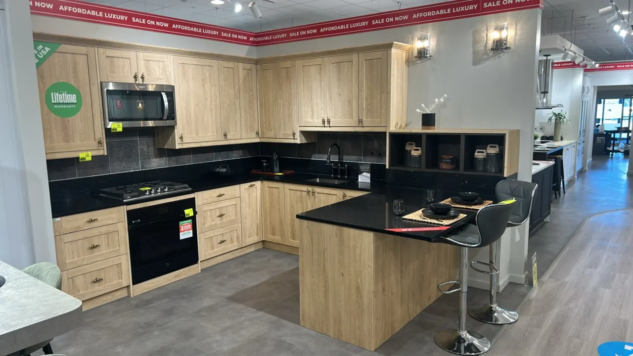 Infinity Plus laminate kitchen cabinets. Features light woodgrain finish upper and lower cabinets, black solid surface countertops, open cubby shelvin