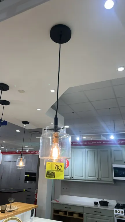 Single-light hanging pendant fixtures. Features tiered clear glass shades, brass-finish lamp sockets, black cords, and matching black ceiling canopies