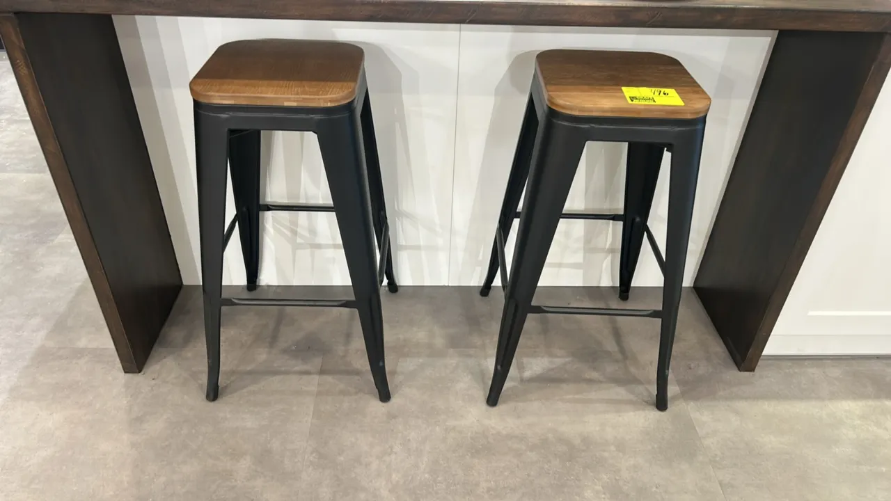 Barstools with wood seats and metal bases. Features square wood seats with rounded corners, black metal frames, and integrated four-sided footrests. C