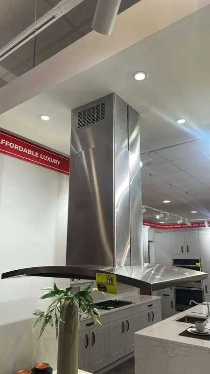 GE Profile PV977N4SS stainless steel island-mount chimney range hood. Features curved canopy, push-button controls, telescopic chimney flue, and integ