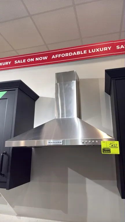 KitchenAid wall-mount chimney range hood. Features stainless steel construction, push-button controls, 3 fan speeds, and integrated underside lighting