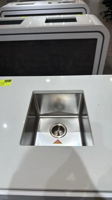 Single-bowl undermount sink, model SI.UKI.SS.01.002. Features stainless steel construction and drain basket strainer assembly. 15". Note: Countertop a