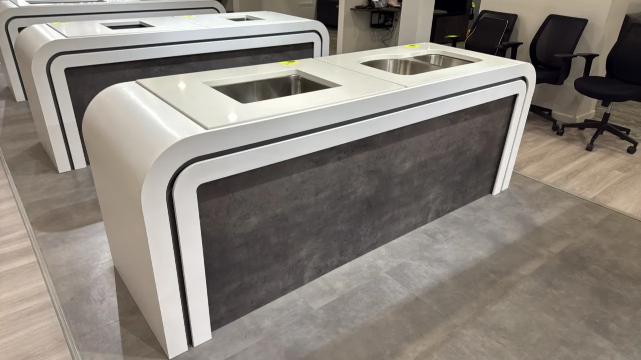 Showroom sink display stands. Features modern curved waterfall framing, white finish with dark textured panels, and dual sink cutouts. 99" x 29.5". Si