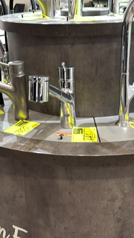 Pull-down kitchen faucet. Features chrome finish, single-lever handle control, and pull-down spray wand. Note: Showroom display fixture; display stand