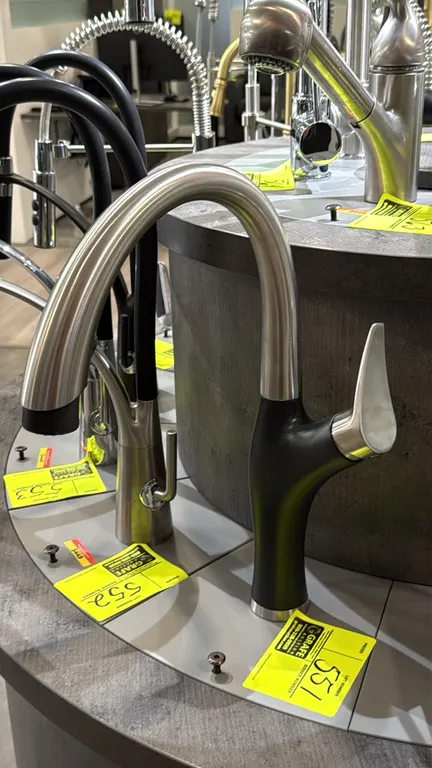 Blanco kitchen faucet. Features a curved gooseneck spout, single-lever handle, pull-down spray head, and dual-tone matte black and stainless steel fin