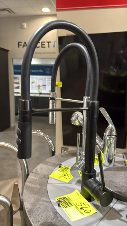 Kura pull-down kitchen faucet. Features a matte black finish, single lever handle, high-arc flexible spout with horizontal support arm, and dual-funct