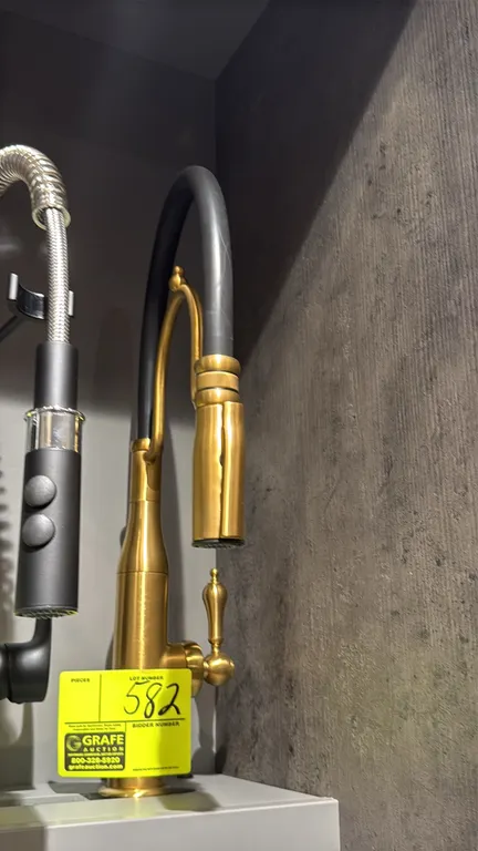 Mekong pull-out kitchen faucet. Features a brushed gold finish, black flexible hose neck, decorative single lever handle, and spray head. Display moun