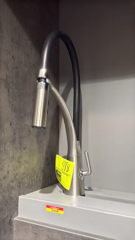 Mackenzie pull-down kitchen faucet. Features a brushed nickel finish, flexible black hose, single-lever handle, and pull-down spray wand. Display stan