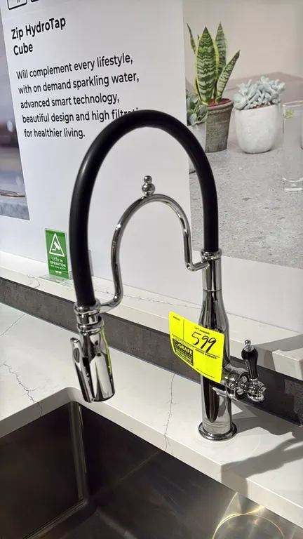 Single-handle pull-down kitchen faucet. Features chrome finish, flexible black hose with arched support arm, pull-down spray wand, and side lever hand