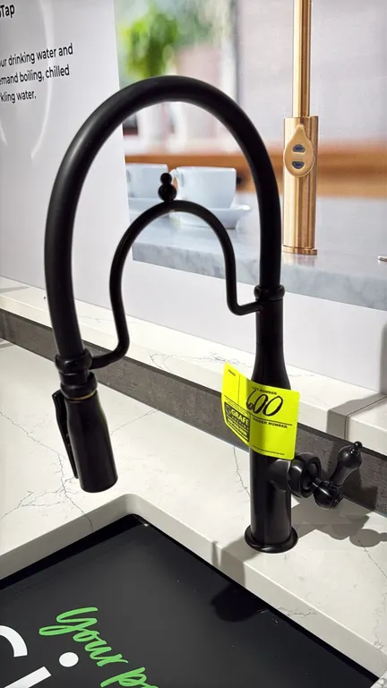 Pull-out kitchen faucet. Features a matte black finish, high-arc spout with decorative bridge accent, single lever handle, and pull-down sprayer wand.