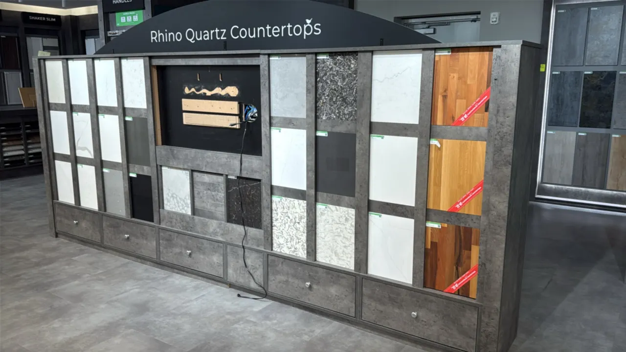 Double-sided countertop material showroom display fixture. Features Rhino Quartz Countertops side with sample slots and lower storage drawers, and Wre