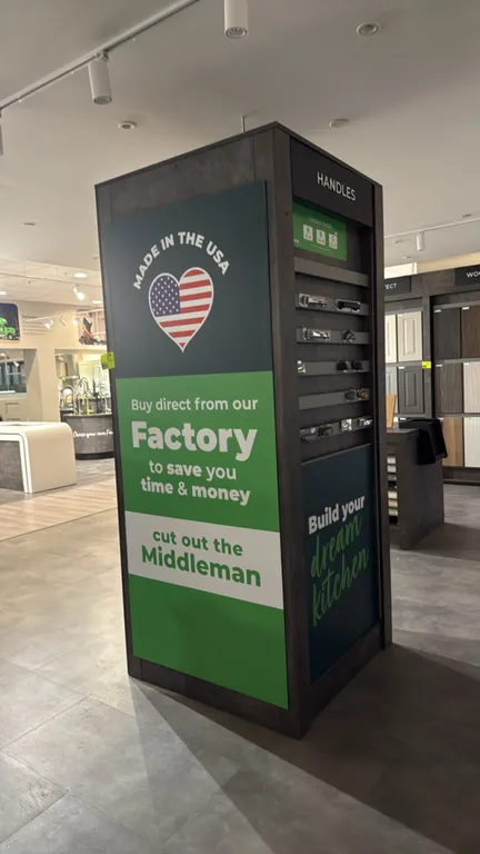 Cabinet hardware display tower. Features 4-sided freestanding kiosk construction with weathered woodgrain laminate finish, retail signage panels, and