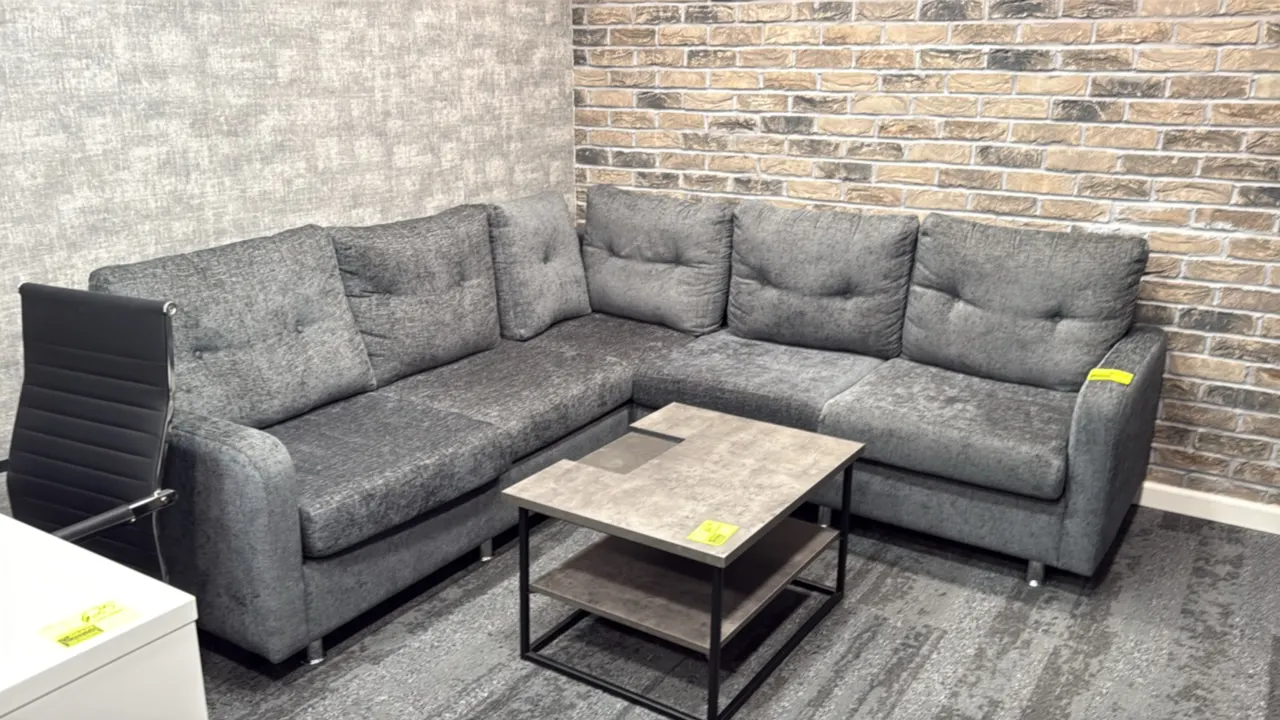 L-shaped sectional sofa. Features gray textured fabric upholstery, tufted back cushions, and cylindrical chrome-tone feet. 87" x 59". Coffee table and