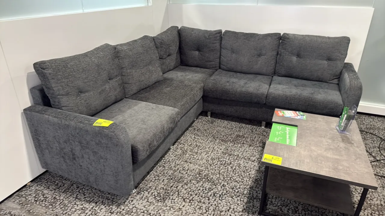 L-shaped sectional couch. Features charcoal gray textured fabric upholstery, tufted back cushions, and silver-tone metal feet. 87" x 59". Coffee table