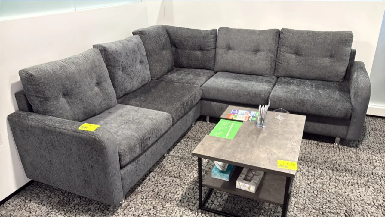L-shaped sectional couch. Features gray textured fabric upholstery, tufted back cushions, and metal legs. 87" x 59". Coffee table and accessories not