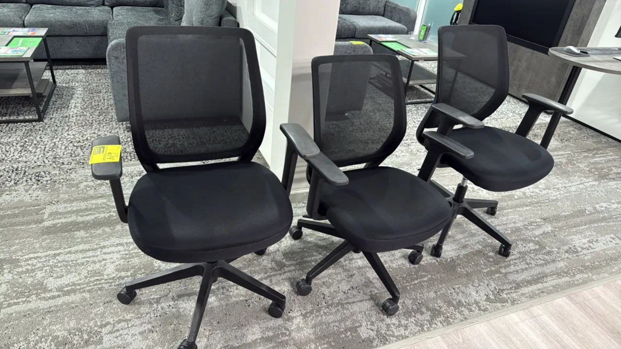 Mesh-back office chairs. Features breathable black mesh backrests, upholstered black fabric seats, armrests, and adjustable seat height. Mounted on 5-