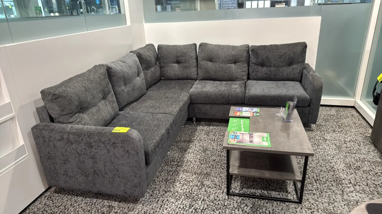 L-shaped sectional couch with coffee table. Couch features gray fabric upholstery with tufted back cushions, measuring 87" x 59". Coffee table feature