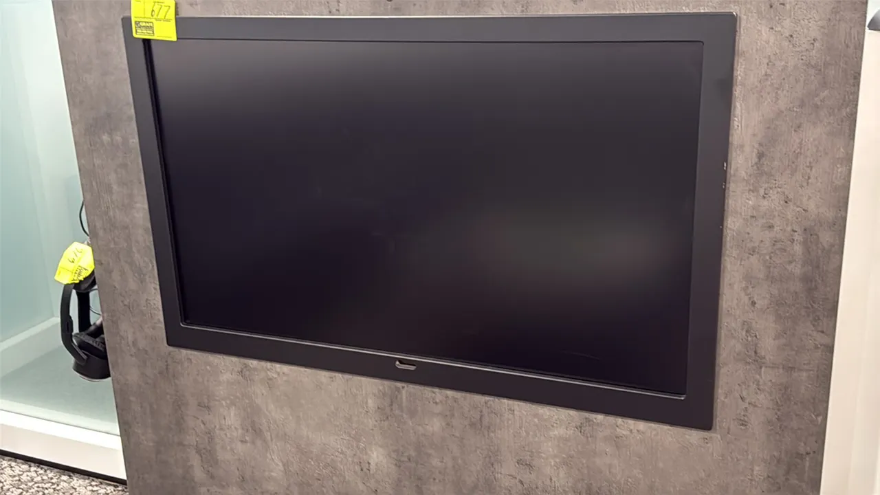 Samsung 50" flat screen color display monitor. Features a black outer frame bezel. Wall-mounted installation. Wall structure and surrounding accessori