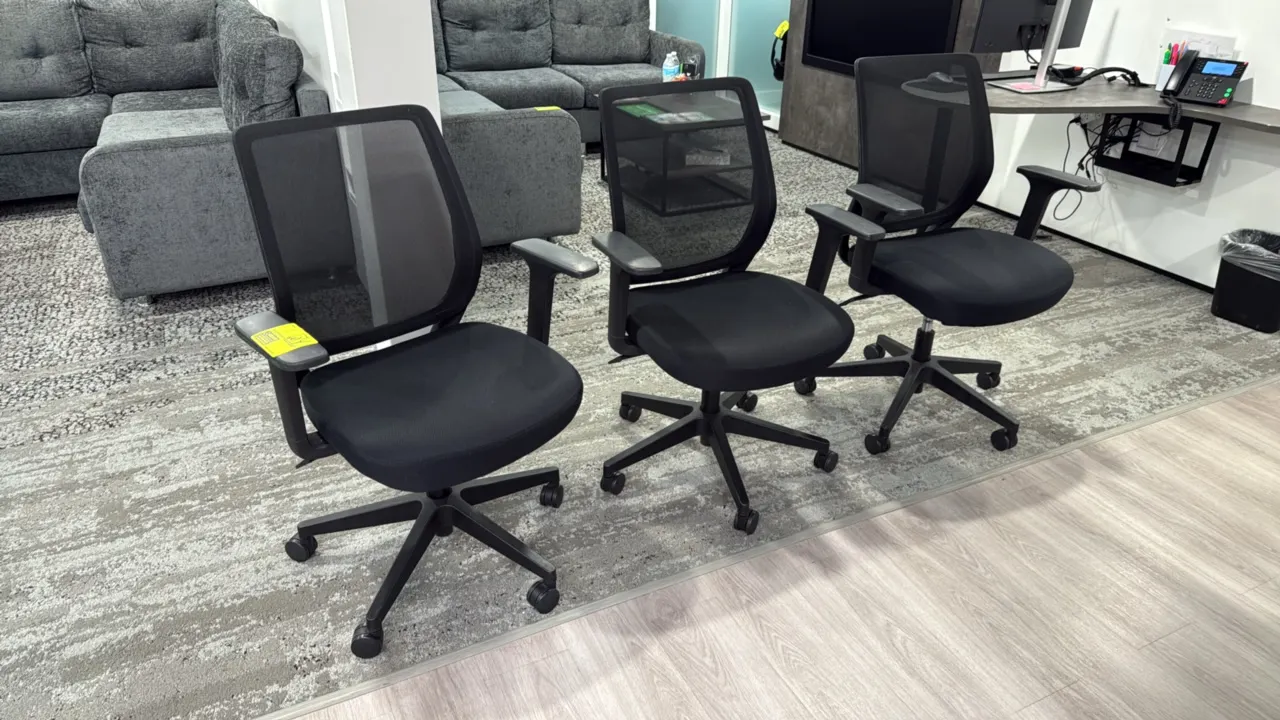 Rolling mesh-back office chairs. Features breathable black mesh backrests, upholstered padded fabric seats, armrests, and pneumatic seat-height adjust