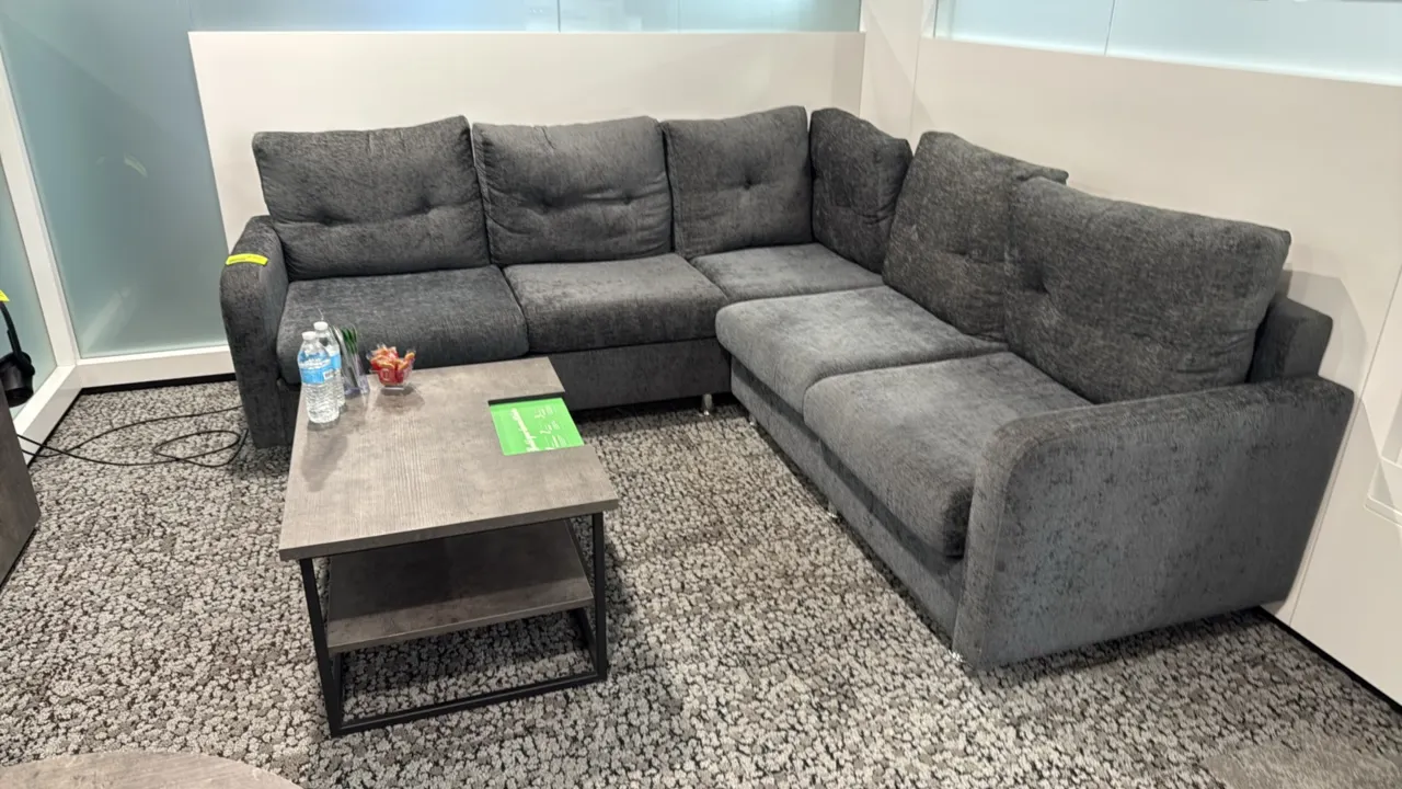 L-shaped sectional couch and coffee table set. Couch features dark gray textured fabric upholstery, tufted back cushions, and chrome-finish legs; meas
