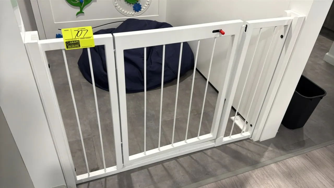 Metal child and pet safety gate. Features white finish, vertical slat design, walk-through swinging door with latch, and side extension panels. 47"W x