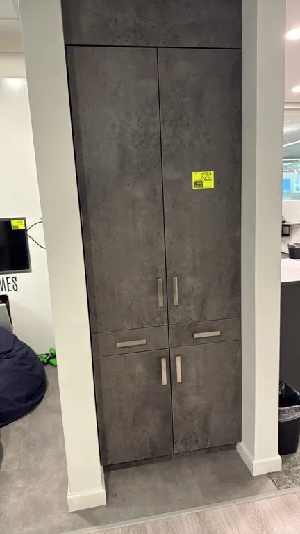 Laminate wall storage cabinet. Features a textured slate gray finish, upper and lower double doors, two center drawers, and brushed metal bar pulls. 3