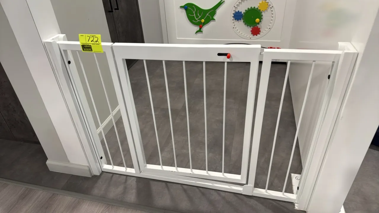 Metal child and pet safety gate. Features center walk-through swinging door with top latch mechanism, side extension panels, and white finish. 47" x 3