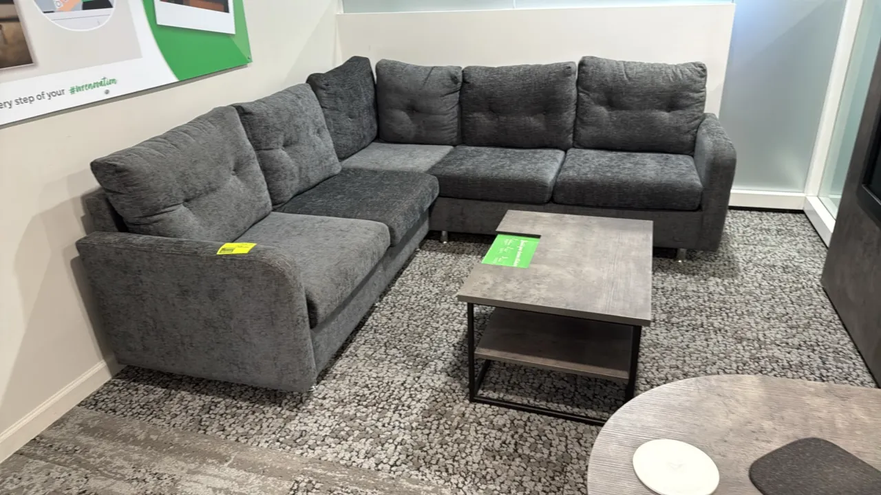 L-shaped sectional sofa and coffee table set. Couch features charcoal gray textured fabric upholstery, tufted back cushions, and metal peg legs. Coffe