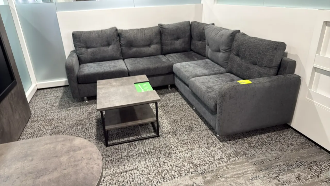 L-shaped sectional couch with coffee table. Couch features dark gray textured fabric upholstery, tufted back cushions, and metal feet; measures 87" x