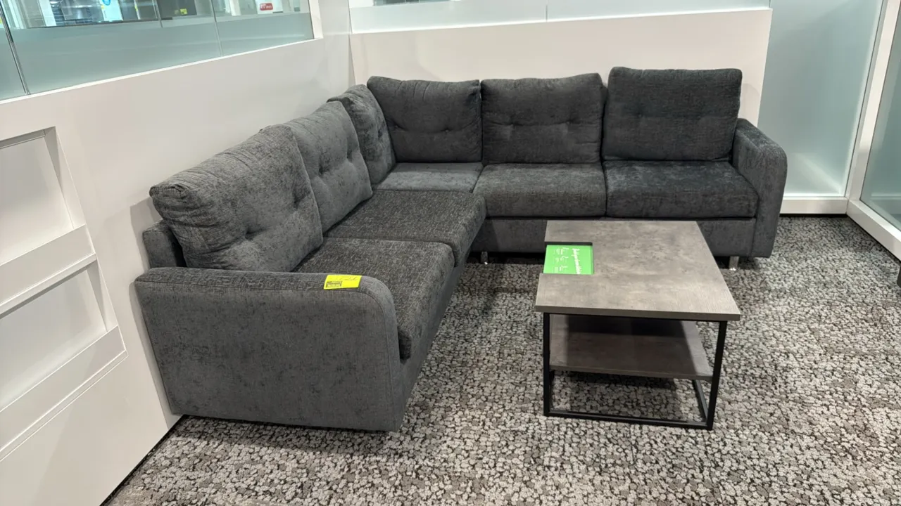L-shaped sectional couch with coffee table. Couch features dark gray textured fabric upholstery, tufted back cushions, and metal legs; measures 87" x