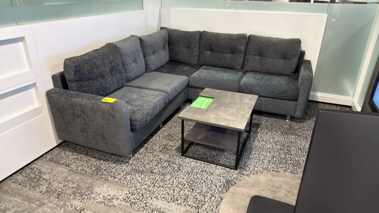 L-shaped sectional couch with coffee table. Couch features gray textured fabric upholstery, tufted back cushions, and chrome-finished legs; measures 8