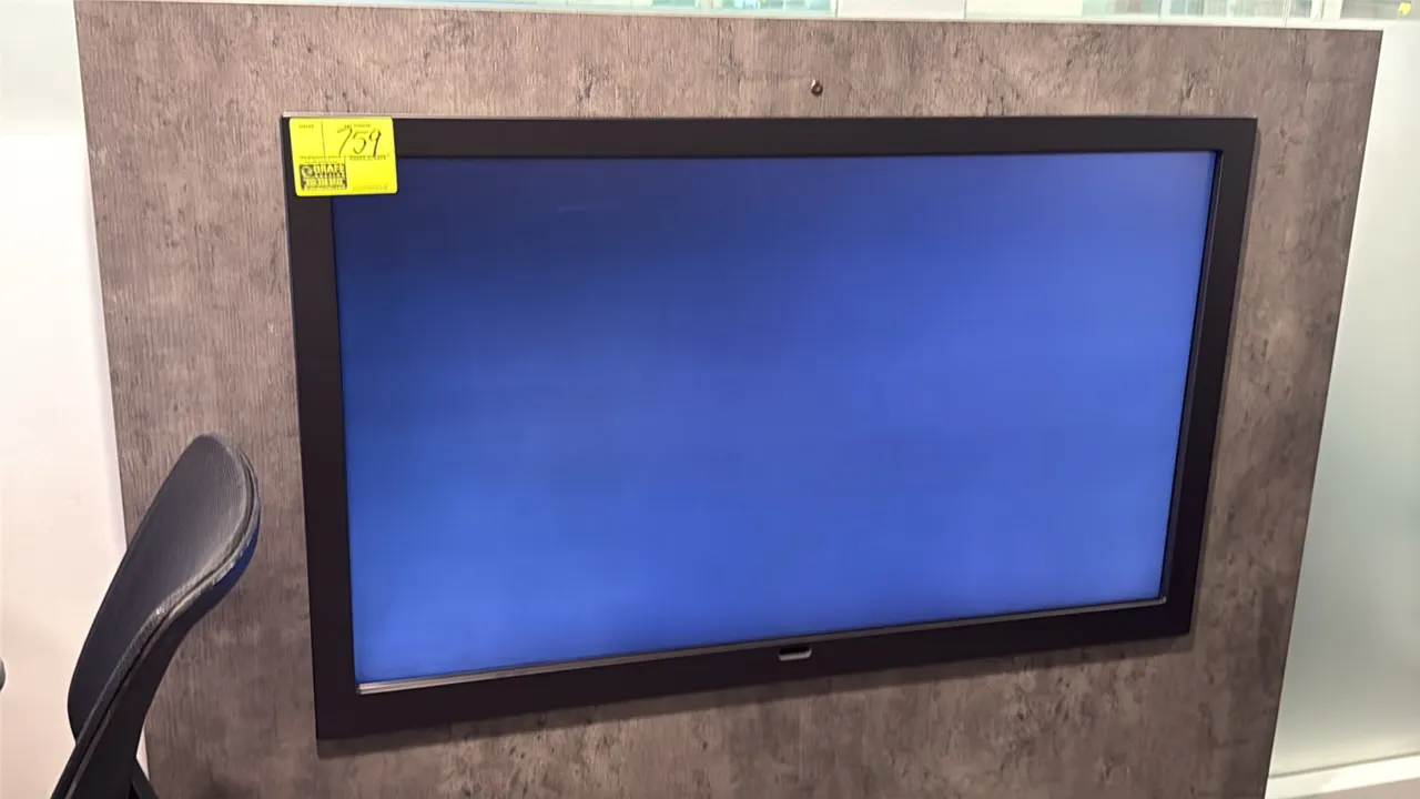 Samsung 50" flat screen display monitor. Features a black bezel. Wall panel and chair not included.