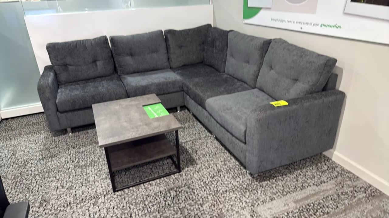 L-shaped sectional sofa with coffee table. Sofa features gray textured fabric upholstery, tufted back cushions, and metal legs; measures 87" x 59". Co