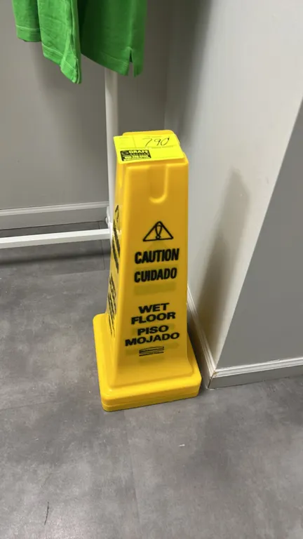 Rubbermaid Commercial Products wet floor safety cone. Features four-sided yellow plastic construction with bilingual "CAUTION CUIDADO / WET FLOOR PISO
