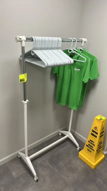 Metal portable clothing rack. Features adjustable height and chrome hanging rail with white metal frame. 3'L. Mounted on casters. Clothing and hangers