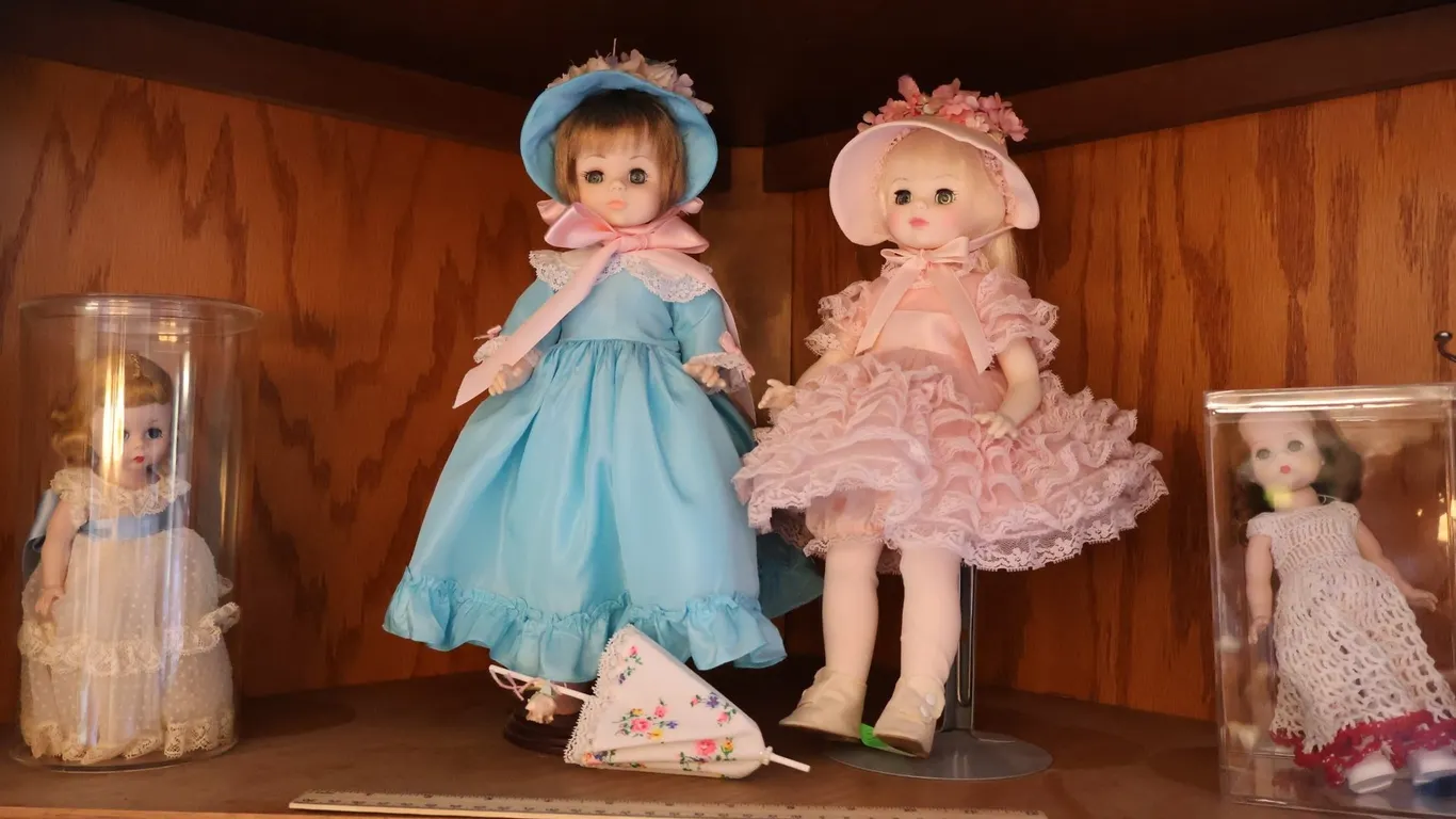 Four Dressed Dolls with Display Cases and Stands
