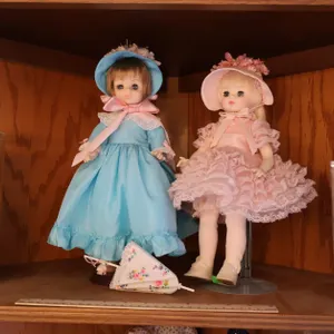 Four Dressed Dolls with Display Cases and Stands