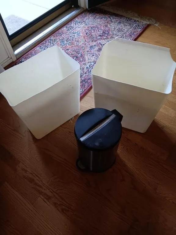 Two plastic and one metal trash cans