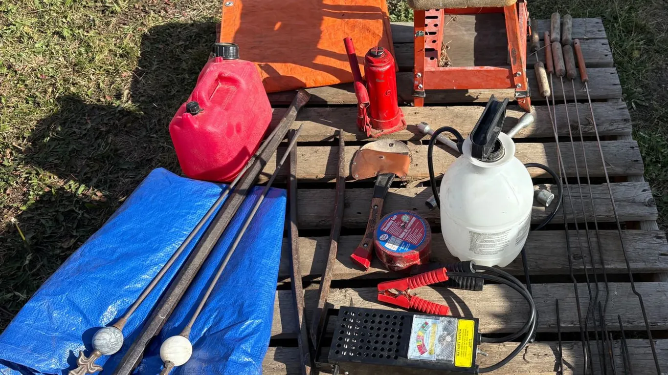 Pallet with weed sprayer, battery tester, bottle jack, axe, work chair, 2 tarps, pry bars, camp fire