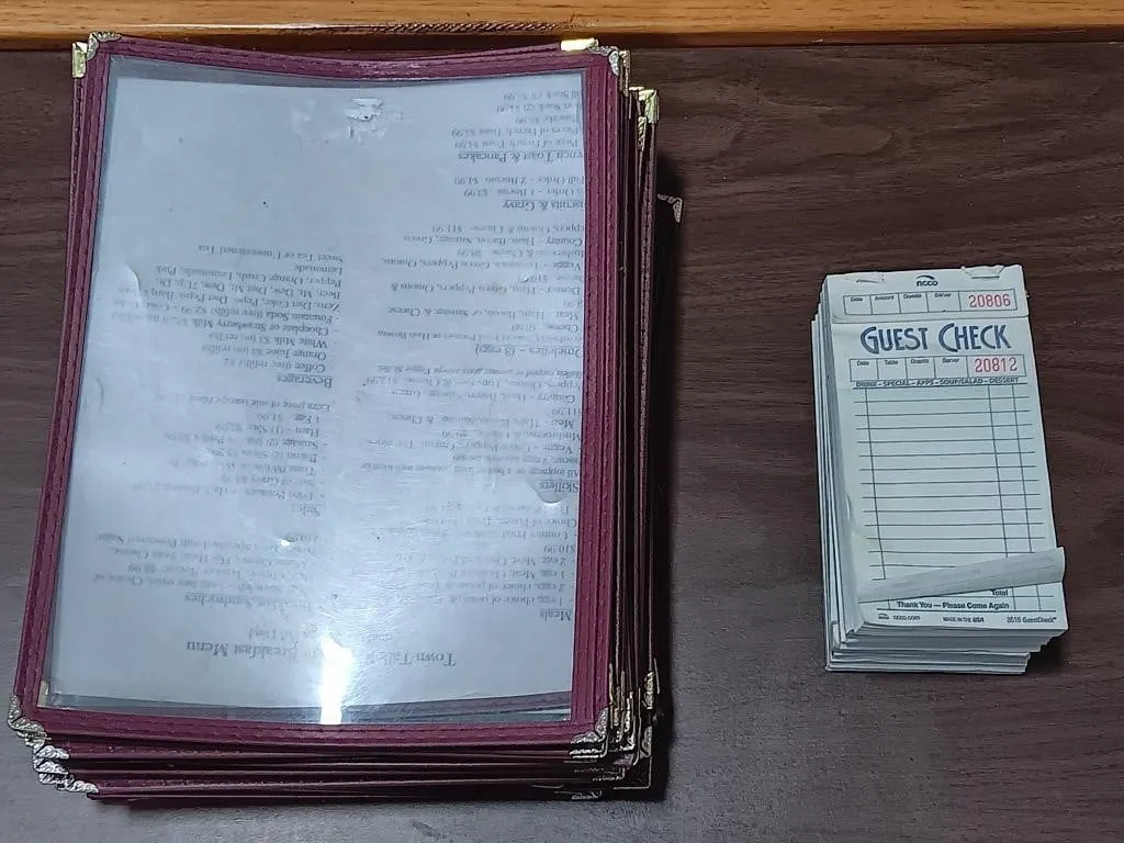 Box of plastic menu pouches and guest check pads.