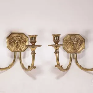Pair of solid brass double candle sconces, each featuring a Sun King motif