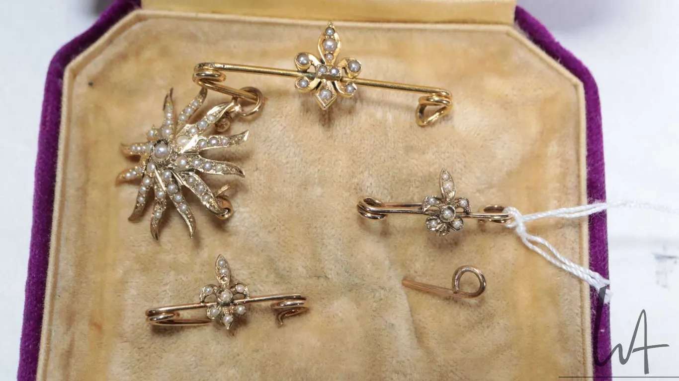 Selection of antique seed pearl jewellery including three fleur-de-lis pines and a sunburst pendant,