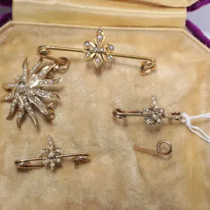 Selection of antique seed pearl jewellery including three fleur-de-lis pines and a sunburst pendant,